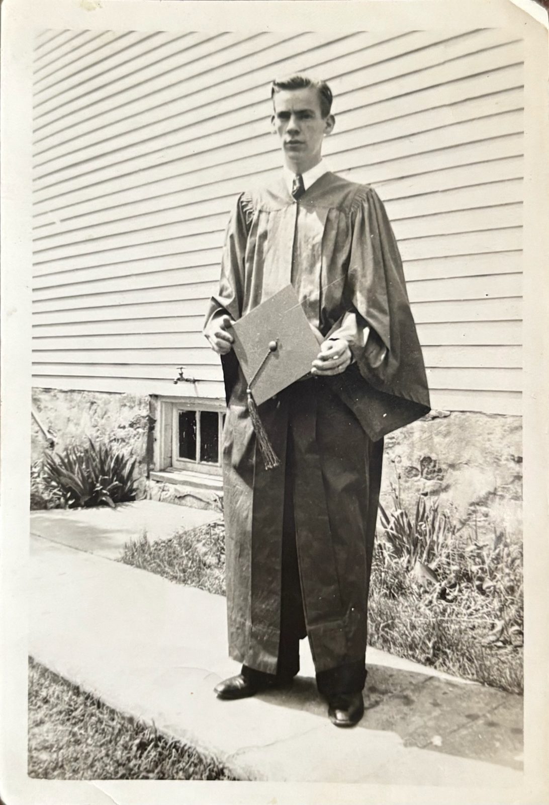 George in cap and gown on graduation day, outside the family home.