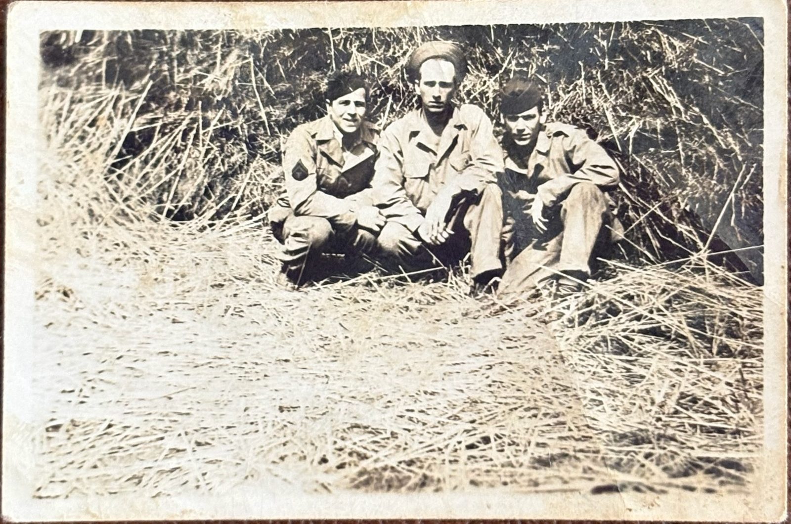 George (right) with two others sitting in a hayfield. Also censor-stamped on the back — same examiner, likely the same envelope home.